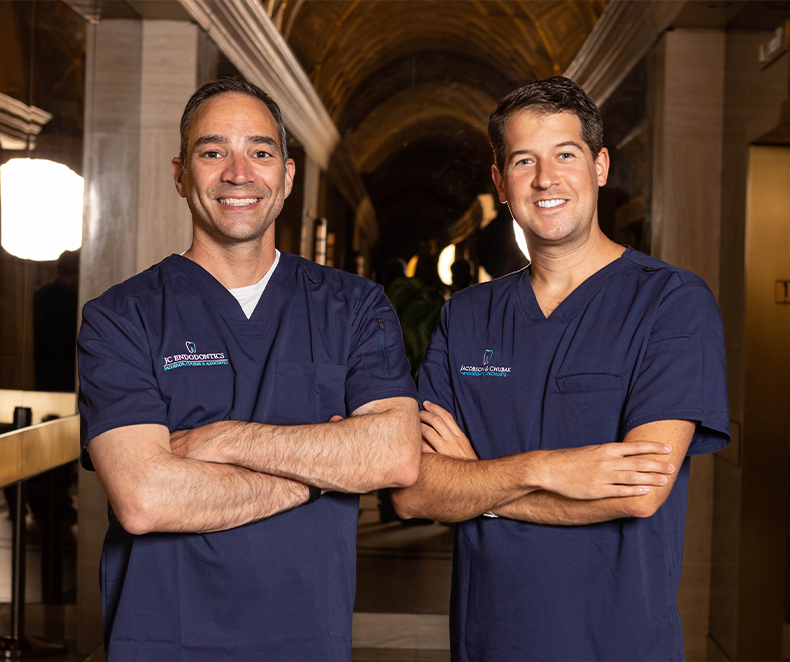 Two smiling New York City endodontists wearing dark blue scrubs